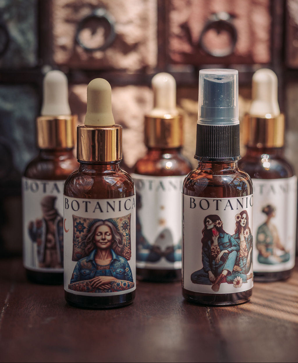 Two amber glass dropper and spray bottles labeled BOTANICAL, with illustrated labels, displayed on a wooden surface in front of a warm-toned apothecary-style cabinet.